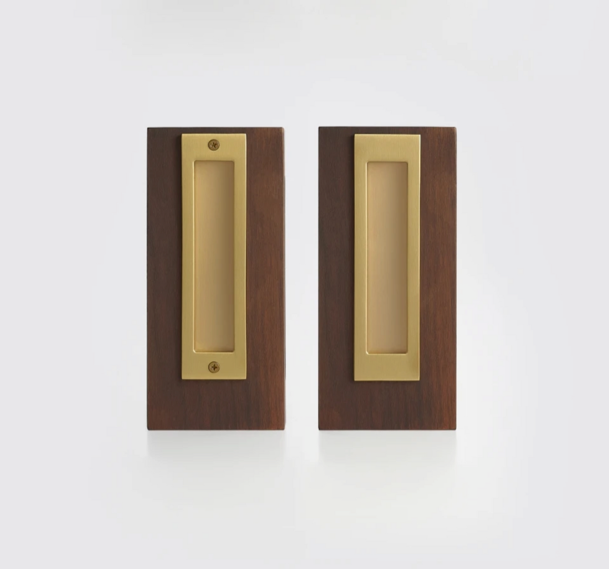 Two matching rectangular pocket door pulls with a brushed brass center plate and a dark brown wood surround, shown side by side on a clean white background.