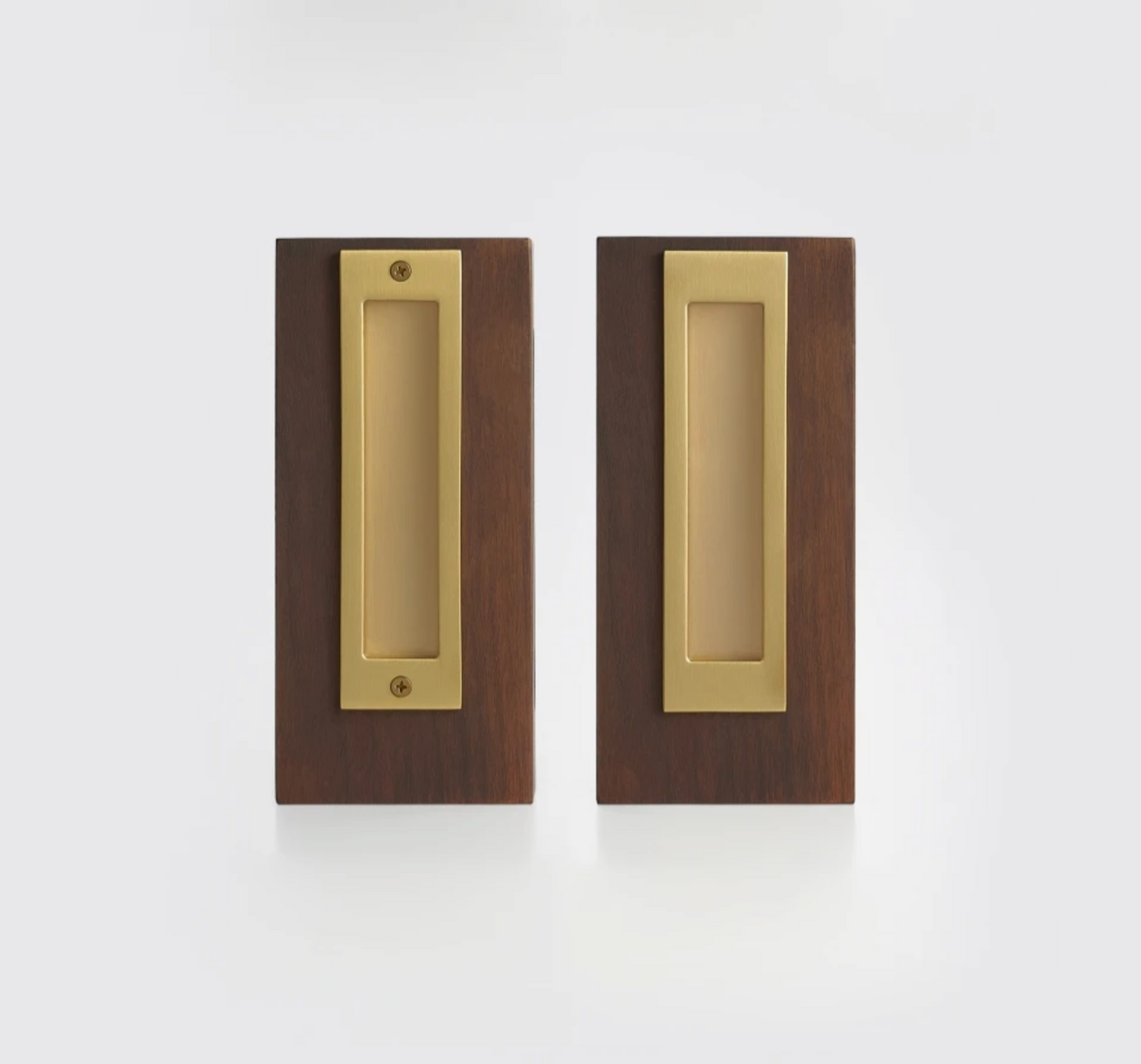 Two matching rectangular pocket door pulls with a brushed brass center plate and a dark brown wood surround, shown side by side on a clean white background.